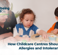 Happy children eating lunch together in a childcare centre with caregivers serving food