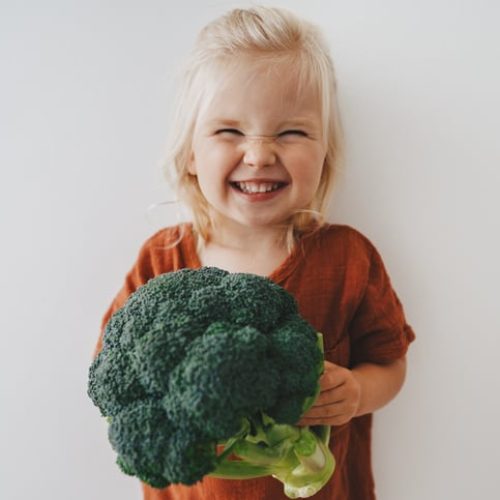 Child girl with broccoli healthy food vegan eating lifestyle organic vegetables plant based diet nutrition funny kid happy smiling